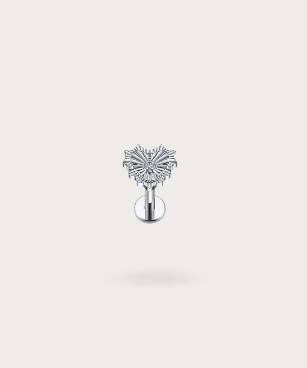 Piercing Trago Con Cuore presentato delicatamente su uno sfondo bianco argentato