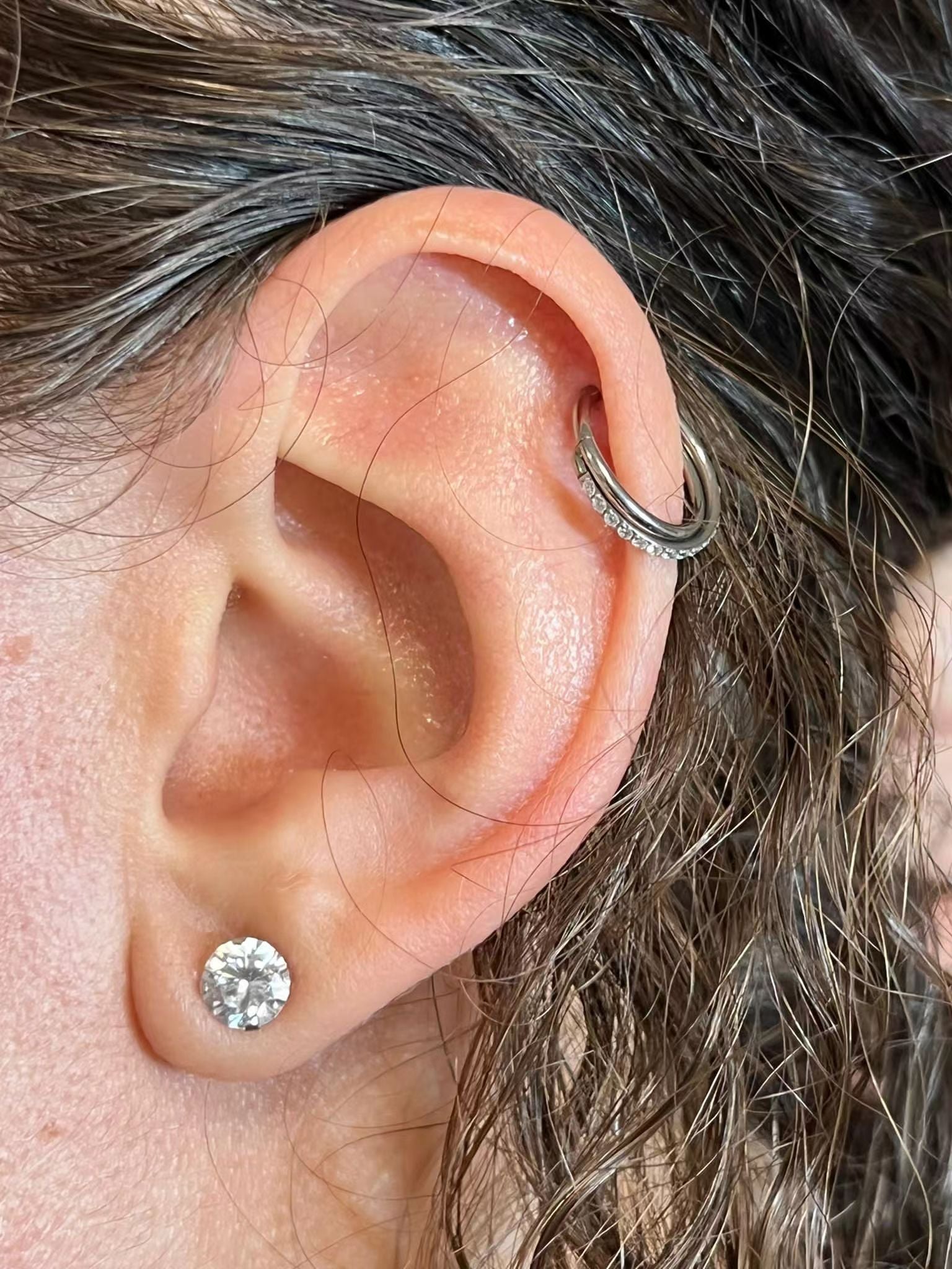 "Orecchino Piercing Daith Anello Incrociato indossato su un orecchio femminile."